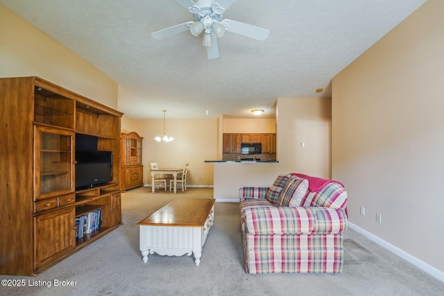 living room featuring a textured ceiling, carpet floors, ceiling fan with notable chandelier, and baseboards