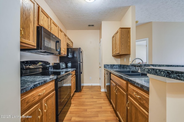 kitchen with light wood finished floors, visible vents, a sink, a textured ceiling, and black appliances