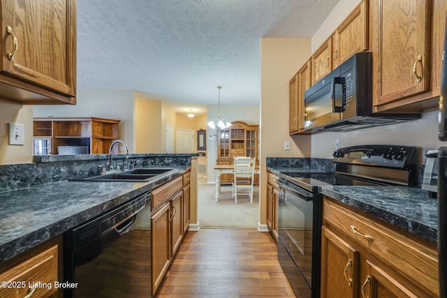 kitchen featuring brown cabinetry, wood finished floors, a textured ceiling, black appliances, and a sink