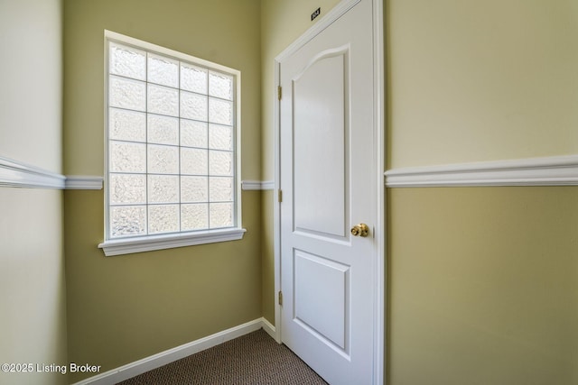 doorway to outside featuring baseboards and dark carpet