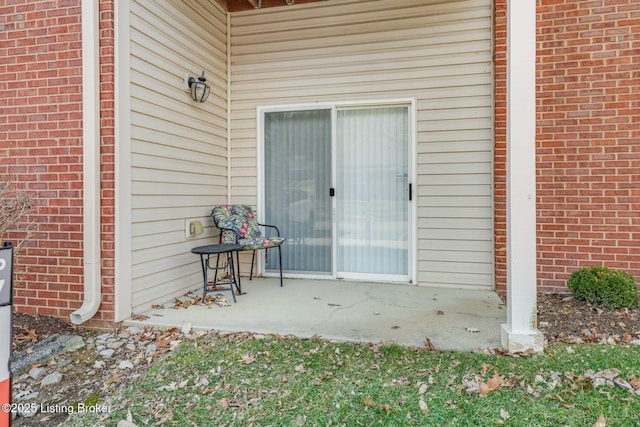 doorway to property with brick siding and a patio