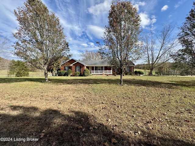 ranch-style house featuring covered porch, brick siding, and a front yard