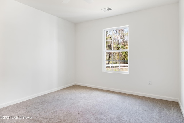 carpeted empty room with a ceiling fan, visible vents, and baseboards