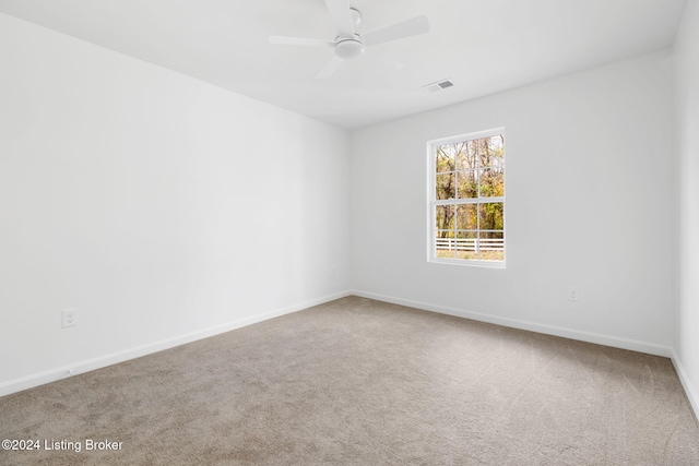 carpeted spare room with a ceiling fan, visible vents, and baseboards