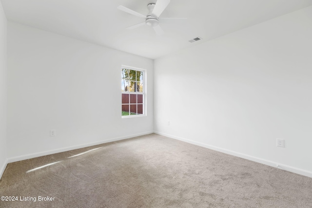 carpeted spare room with ceiling fan, visible vents, and baseboards