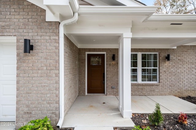 property entrance featuring a garage, brick siding, and covered porch