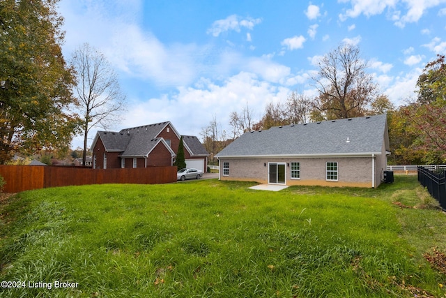 rear view of property featuring central AC, fence, brick siding, and a lawn