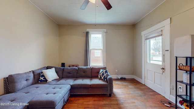 living area with baseboards, ceiling fan, and wood finished floors