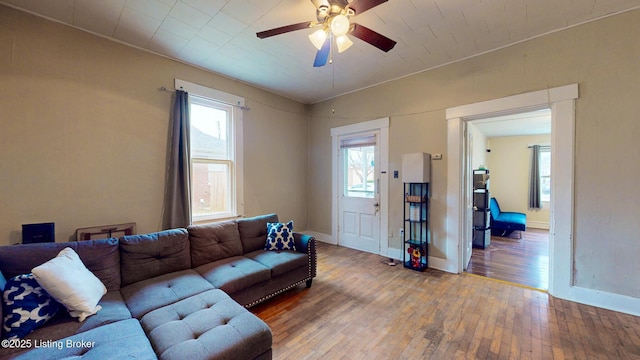 living room featuring a ceiling fan, a healthy amount of sunlight, baseboards, and wood-type flooring