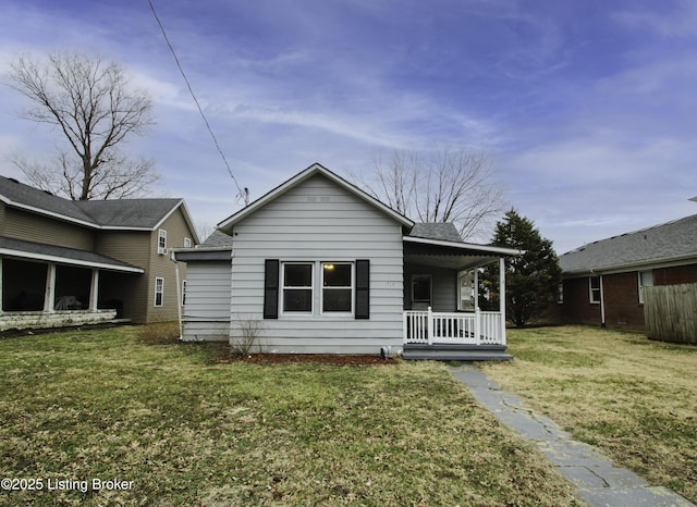 rear view of house featuring a porch and a lawn