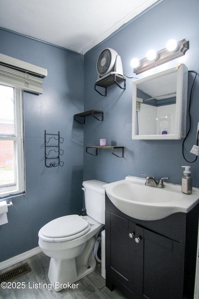 bathroom with vanity, toilet, wood finished floors, and visible vents