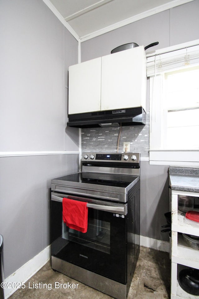 kitchen featuring under cabinet range hood, crown molding, electric stove, and concrete flooring