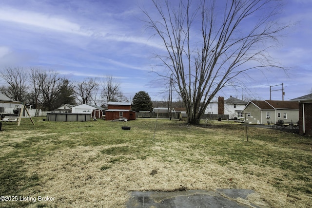 view of yard with an outdoor pool, a residential view, an outdoor structure, and fence