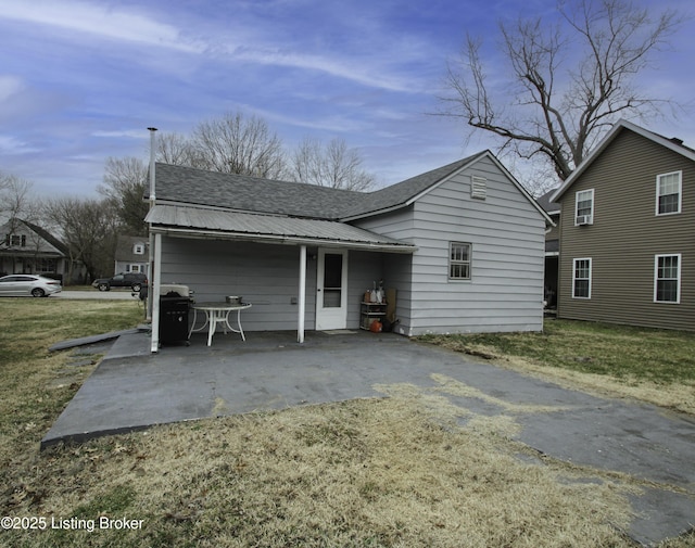 back of property featuring a patio, a lawn, and metal roof