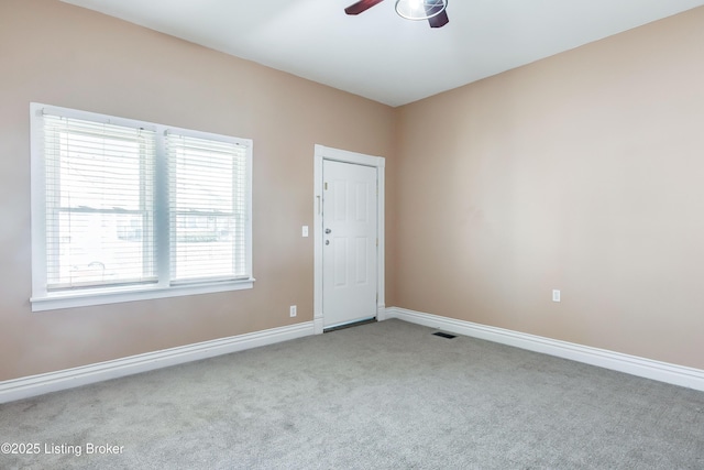 empty room with carpet flooring, a ceiling fan, and baseboards