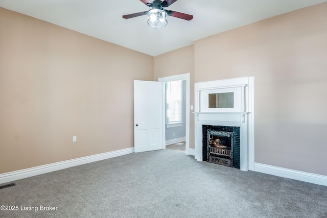 unfurnished living room featuring carpet floors, a fireplace, visible vents, a ceiling fan, and baseboards