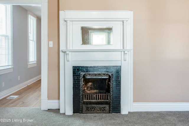 interior details featuring carpet flooring, a fireplace, visible vents, and baseboards