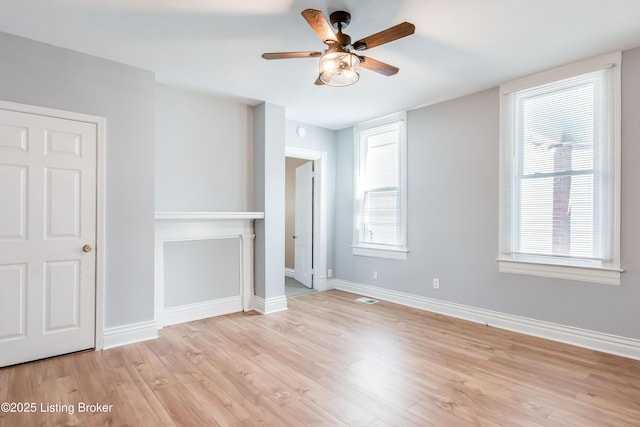 unfurnished room featuring light wood-type flooring, visible vents, baseboards, and a ceiling fan