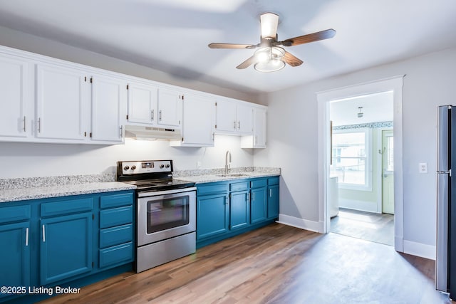 kitchen featuring blue cabinets, under cabinet range hood, a sink, white cabinets, and appliances with stainless steel finishes