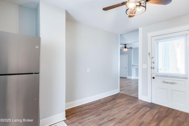 kitchen featuring a ceiling fan, freestanding refrigerator, baseboards, and wood finished floors