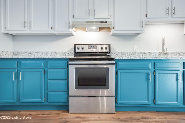 kitchen with under cabinet range hood, blue cabinetry, light wood-style floors, and stainless steel electric stove