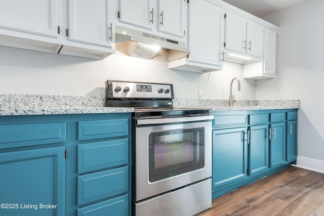 kitchen with stainless steel range with electric stovetop, blue cabinets, under cabinet range hood, and wood finished floors