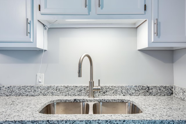 details featuring a sink and light stone countertops