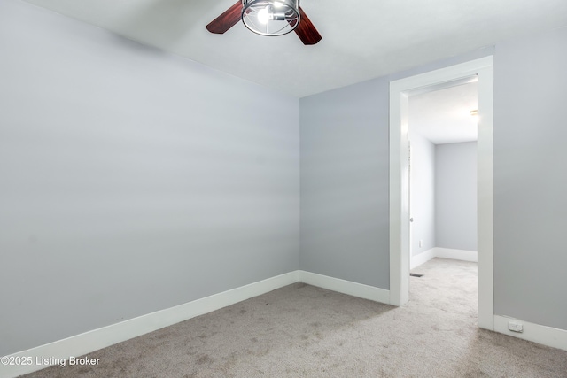 carpeted spare room featuring baseboards and a ceiling fan