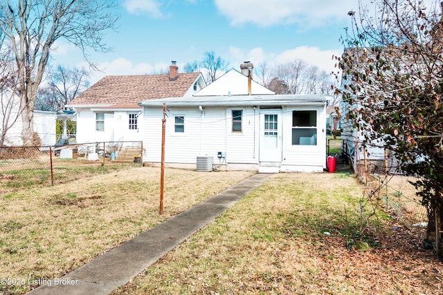 back of property with central AC unit, a shingled roof, fence, a yard, and a chimney