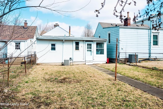 back of house featuring central air condition unit, fence, and a yard