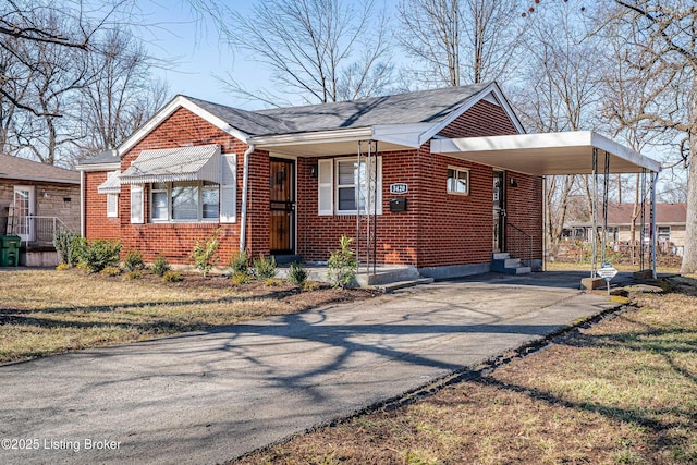 view of side of property with entry steps, a carport, aphalt driveway, and brick siding