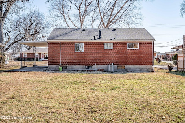 rear view of house with a lawn, a carport, and brick siding