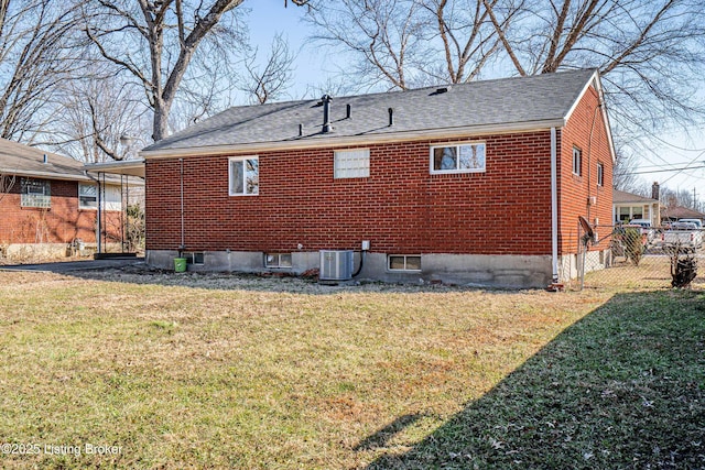 rear view of house featuring brick siding, a lawn, fence, and central AC unit