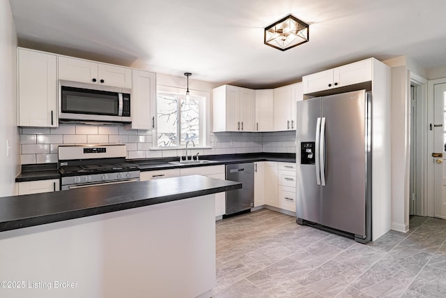 kitchen with stainless steel appliances, dark countertops, white cabinetry, and a sink