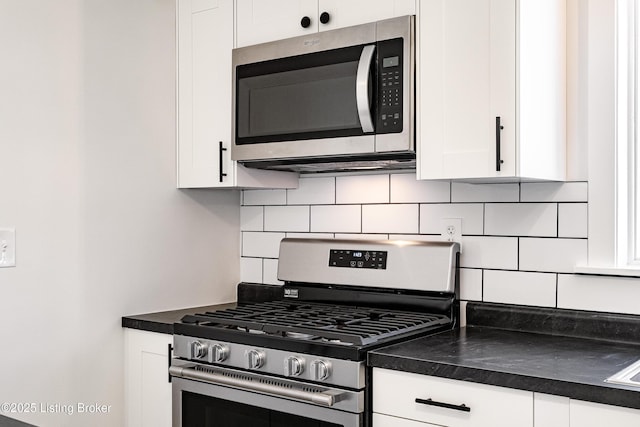 kitchen featuring appliances with stainless steel finishes, dark countertops, white cabinetry, and decorative backsplash