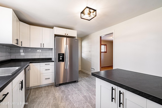 kitchen with stainless steel appliances, dark countertops, white cabinets, and backsplash