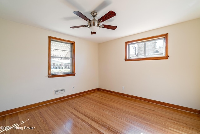 empty room with light wood-type flooring, plenty of natural light, a ceiling fan, and baseboards