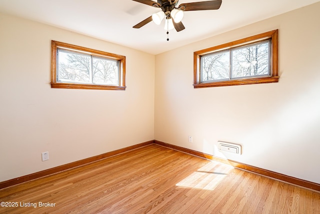 spare room with ceiling fan, light wood-style flooring, and baseboards