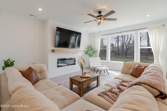 living area featuring carpet, visible vents, a glass covered fireplace, and recessed lighting