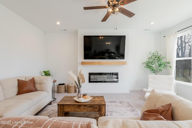 living area with baseboards, a glass covered fireplace, ceiling fan, carpet floors, and recessed lighting