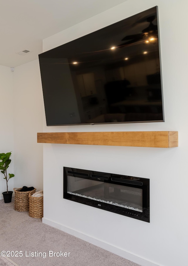 interior details featuring a glass covered fireplace, visible vents, and carpet