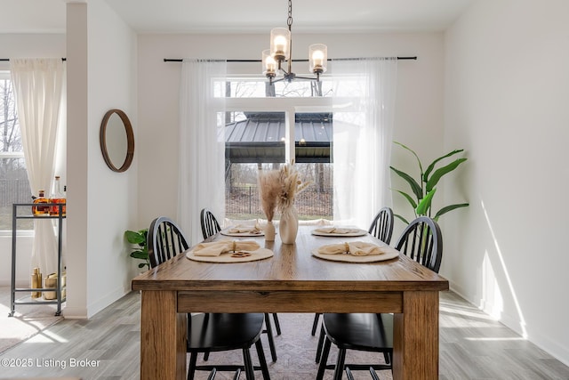 dining space with a chandelier, light wood finished floors, baseboards, and a healthy amount of sunlight