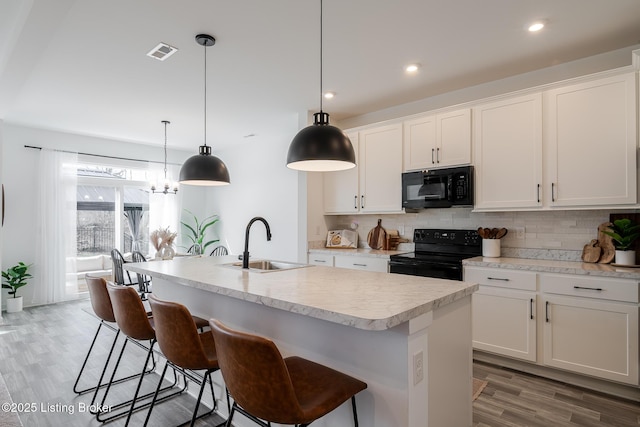 kitchen featuring tasteful backsplash, visible vents, light countertops, black appliances, and a sink