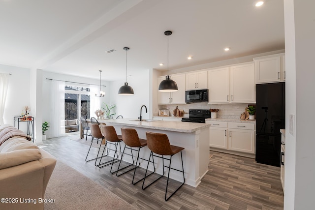 kitchen featuring a breakfast bar area, decorative backsplash, white cabinets, a sink, and black appliances