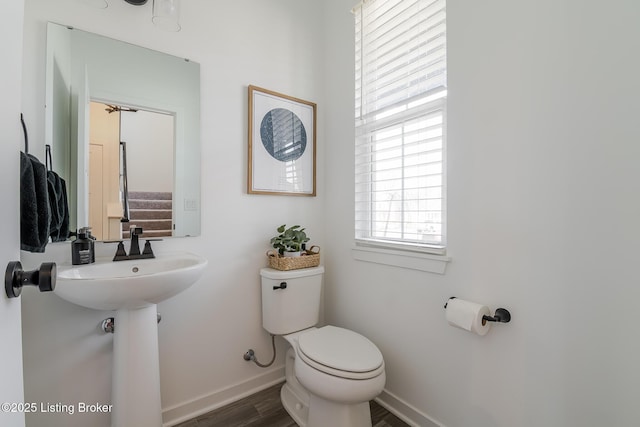 bathroom with baseboards, a sink, toilet, and wood finished floors