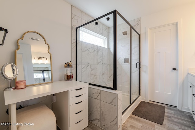 full bathroom featuring visible vents, a shower stall, vanity, and wood finished floors