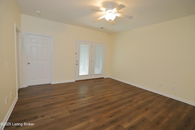 spare room with ceiling fan, dark wood-type flooring, and baseboards