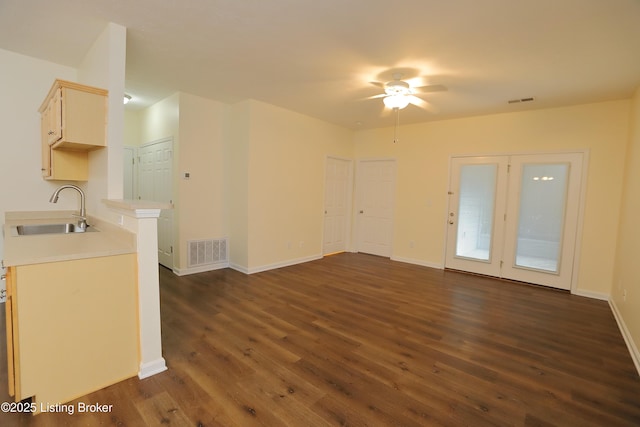 unfurnished living room with dark wood-style floors, baseboards, visible vents, and a sink