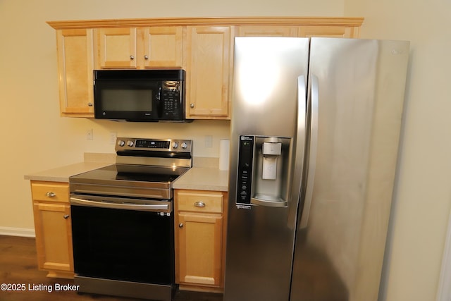 kitchen featuring stainless steel appliances, light countertops, light brown cabinetry, dark wood-type flooring, and baseboards