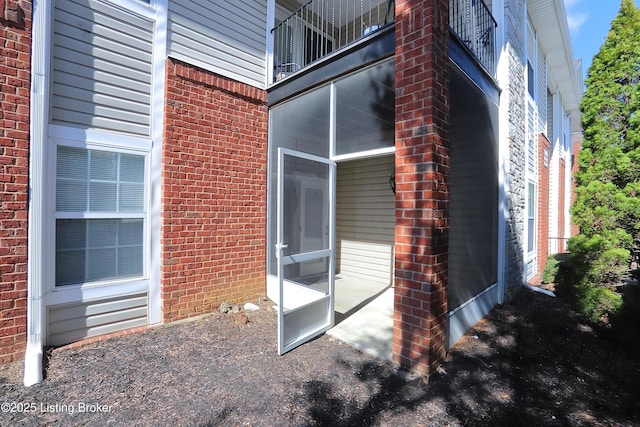 exterior space featuring brick siding and a balcony